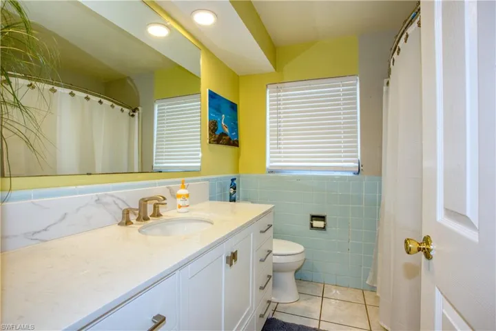 Bathroom featuring tile patterned flooring, vanity, tile walls, and toilet