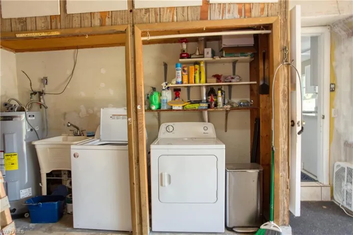 Clothes washing area with electric & water heater, sink, and washing machine and clothes dryer