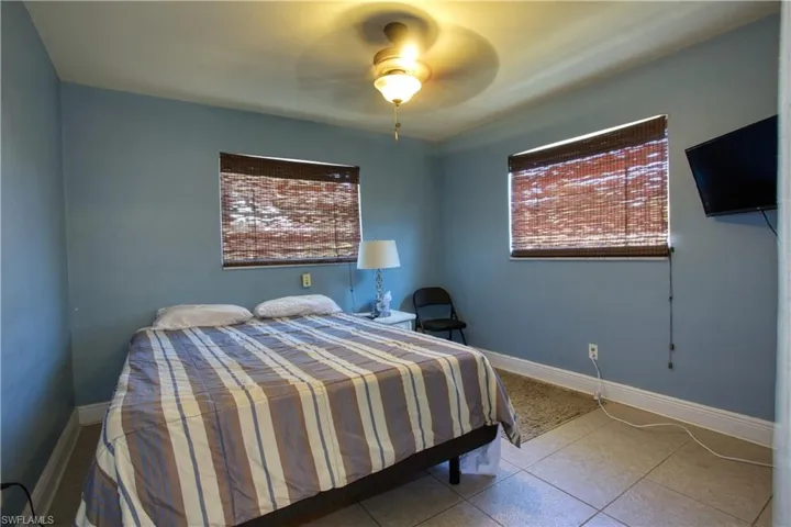 Tiled bedroom with ceiling fan and multiple windows