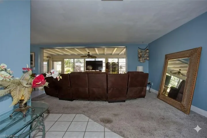 Living room with light colored carpet, ceiling fan, and light tile patterned floors