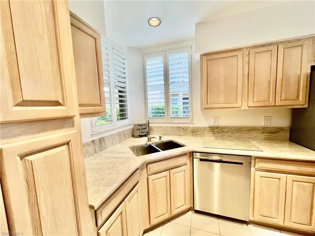 Kitchen with stainless steel dishwasher, light brown cabinetry, a sink, light countertops, and recessed lighting