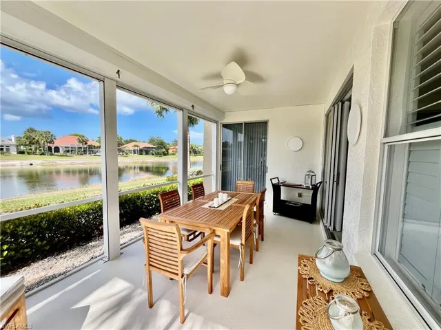 Sunroom with a water view, a textured wall, a ceiling fan, outdoor dining area, and a residential view