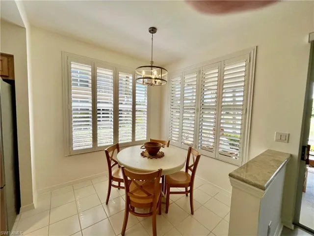 Dining space with a chandelier, light tile patterned floors, and baseboards