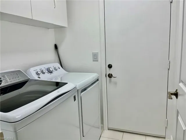 Laundry room with washer and dryer, cabinet space, and light tile patterned flooring