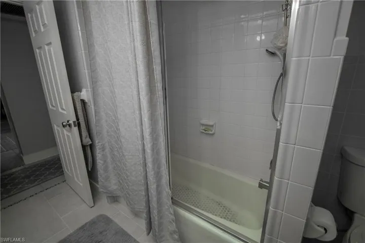 Bathroom featuring tile patterned flooring, toilet, and shower / bath combo with shower curtain