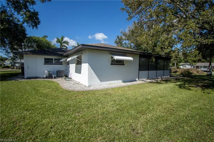 Rear view of property featuring a lawn and central air condition unit