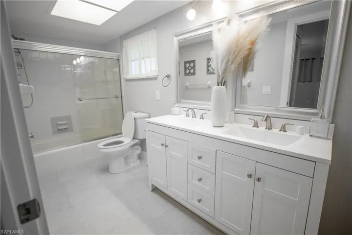 Full bathroom featuring vanity, tile patterned flooring, toilet, and combined bath / shower with glass door