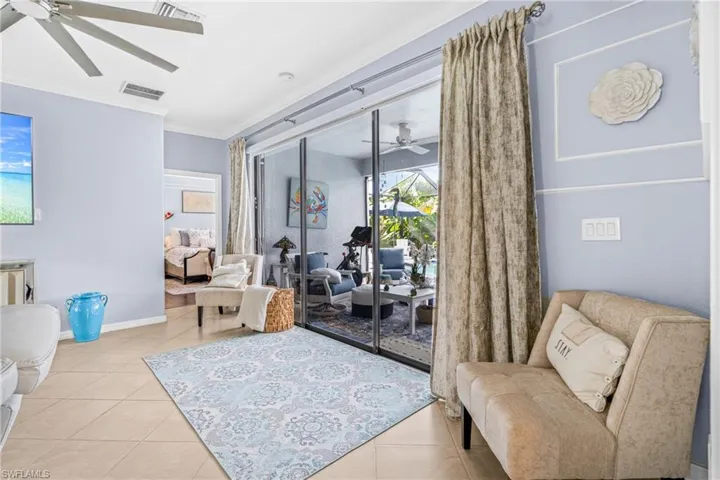 Living area featuring a ceiling fan, ornamental molding, and light tile patterned flooring