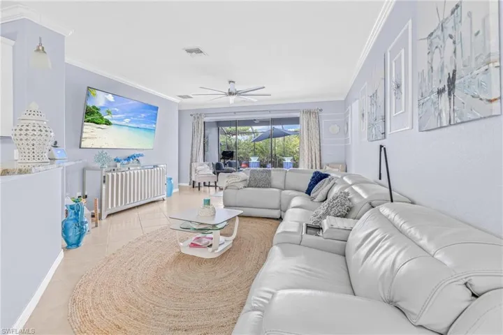 Living area featuring ornamental molding, ceiling fan, and light tile patterned floors