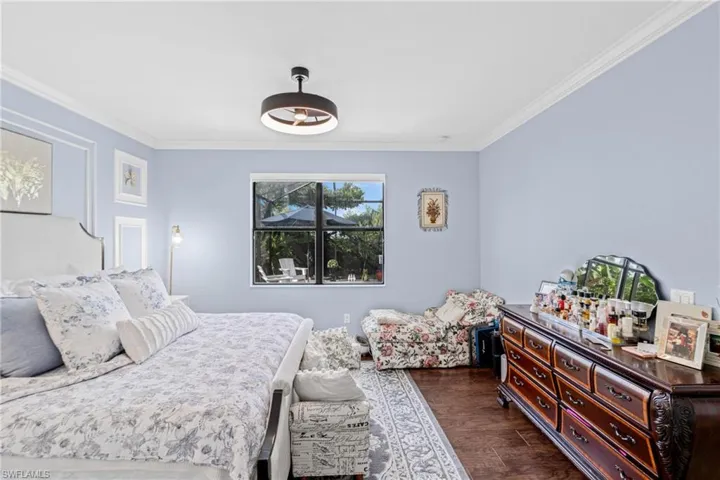 Bedroom with dark wood-style floors and crown molding