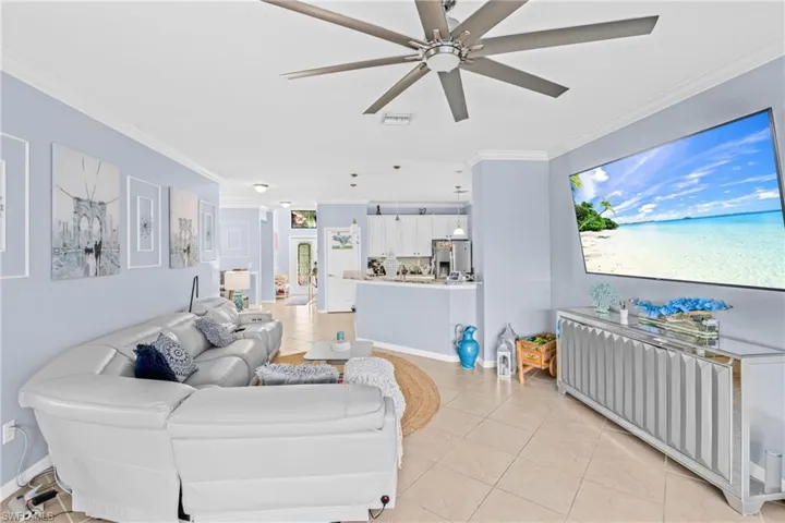 Living area featuring crown molding, light tile patterned flooring, and a ceiling fan