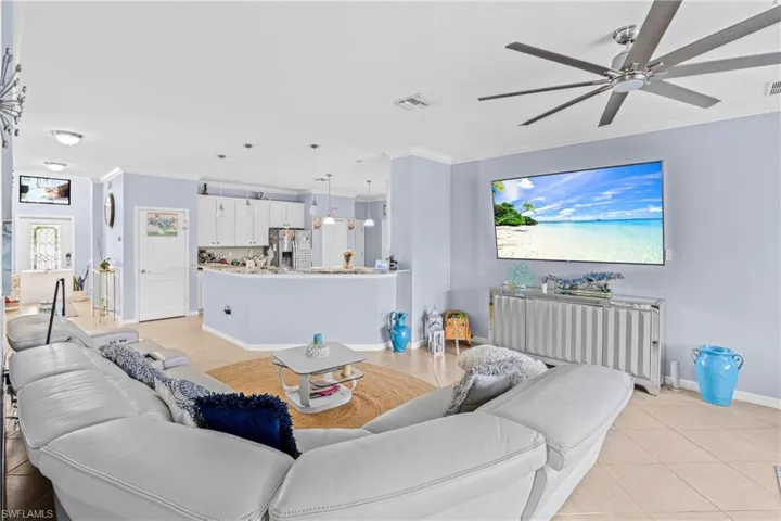 Living area with crown molding, light tile patterned floors, ceiling fan, and radiator
