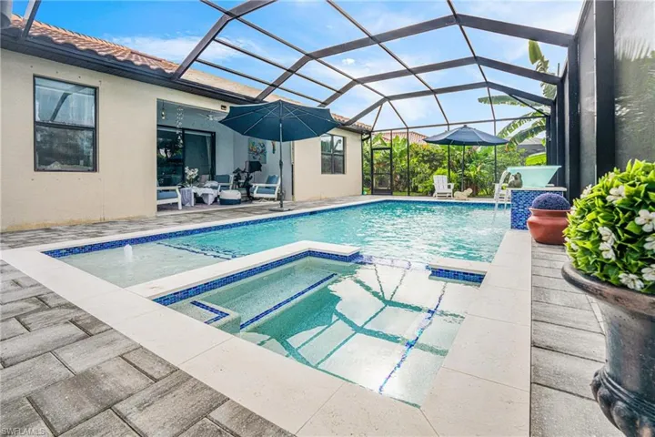 Combined pool / hot tub featuring a sunroom, a patio area, a lanai, and outdoor seating
