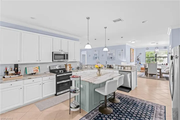 Kitchen featuring ornamental molding, stainless steel appliances, hanging light fixtures, light stone countertops, and a peninsula