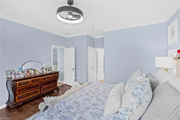 Bedroom with ornamental molding, wood finished floors, and ceiling fan