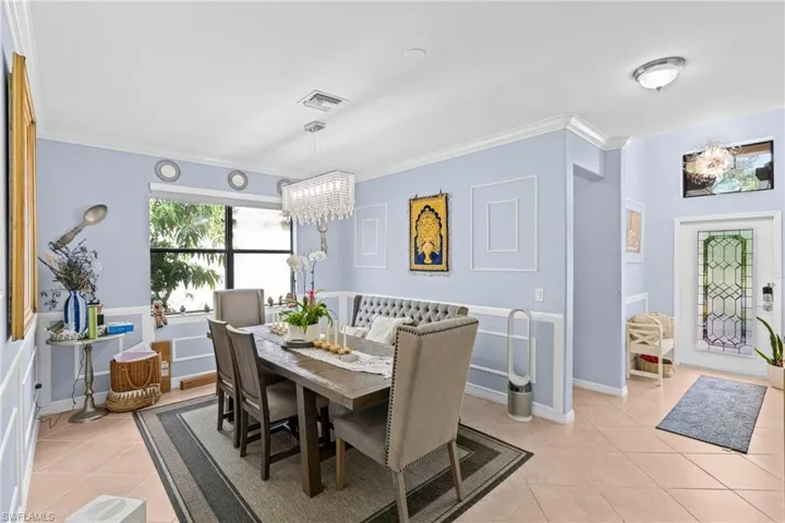 Dining area featuring hanging lights, ornamental molding, light tile patterned floors, and a decorative wall
