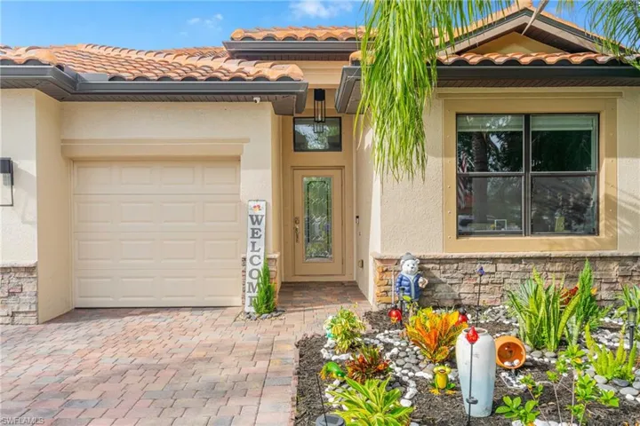 Property entrance with a tile roof, stone siding, stucco siding, and a garage