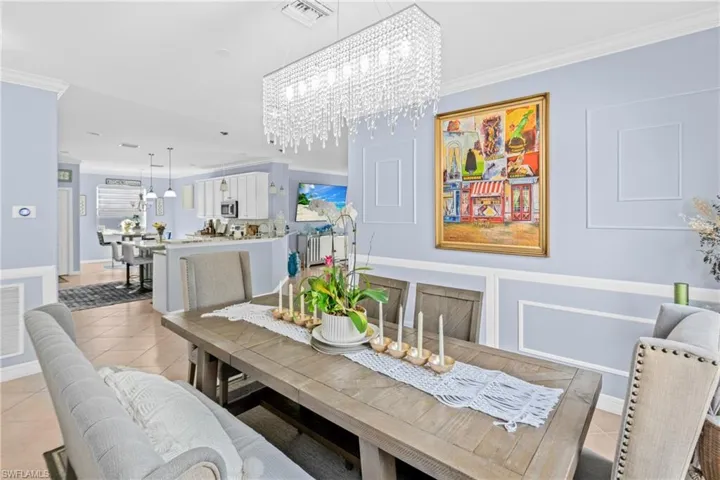 Dining room with ornamental molding, a chandelier, light tile patterned floors, and a decorative wall