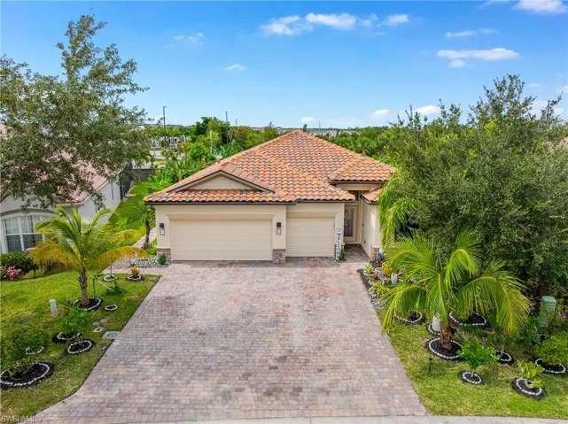 Mediterranean / spanish home featuring stucco siding, a tile roof, driveway, a garage, and stone siding