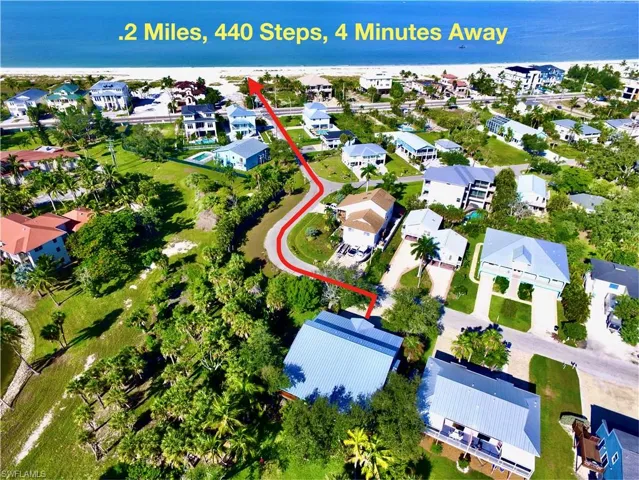 Aerial perspective showcasing a coastal neighborhood with lush landscaping and proximity to a sandy beach