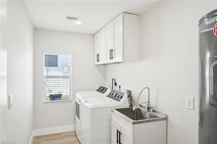 Clothes washing area with washer and dryer, light wood finished floors, cabinet space, baseboards, and recessed lighting