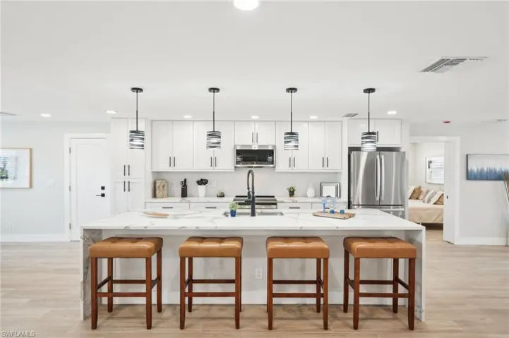 Kitchen with stainless steel appliances, recessed lighting, baseboards, light stone countertops, and white cabinetry
