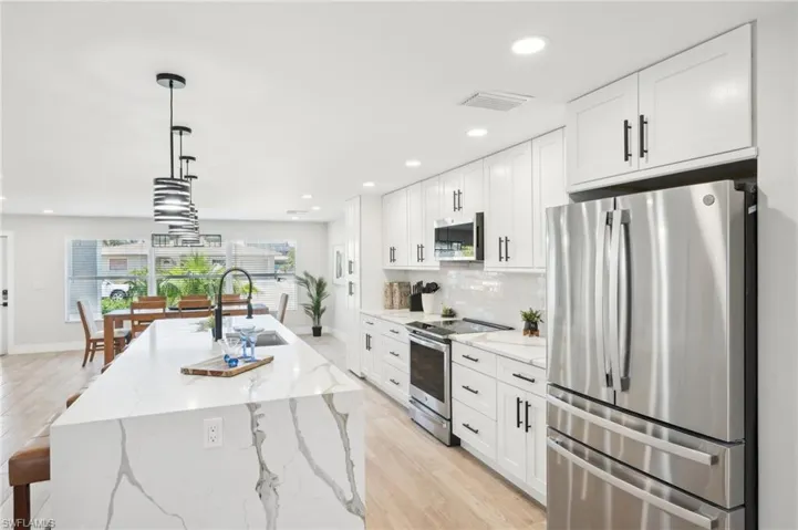 Kitchen featuring stainless steel appliances, a sink, white cabinetry, light wood-style floors, and recessed lighting