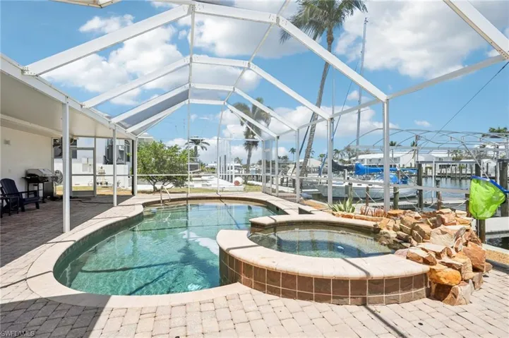 View of swimming pool featuring a patio area, a lanai, a boat dock, and a pool with connected hot tub