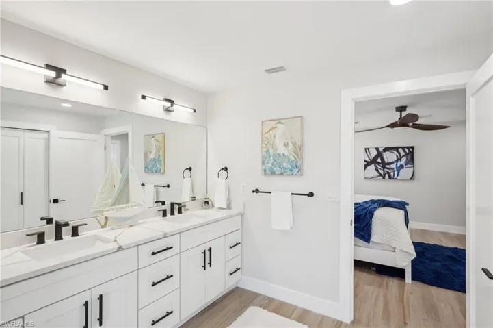 Ensuite bathroom with baseboards, wood finished floors, double vanity, and ceiling fan