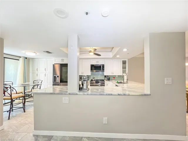 View from entry hall into kitchen.  New upgraded appliances, beautiful cabinetry.  Notice large pantry cabinets.  Sliders opening onto front lanai allow for easy entertaining traffic flow throughout.