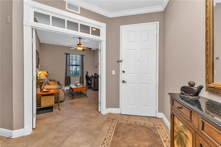 Entrance foyer featuring inlaid floor details, ceiling fan, ornamental molding, and light tile patterned floors