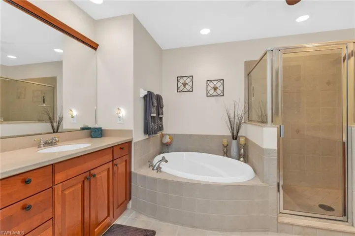 Full bathroom featuring a shower stall, vanity, a garden tub, light tile patterned flooring, and recessed lighting