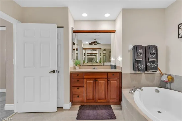 Bathroom featuring vanity, a bath, light tile patterned floors, ceiling fan, and recessed lighting