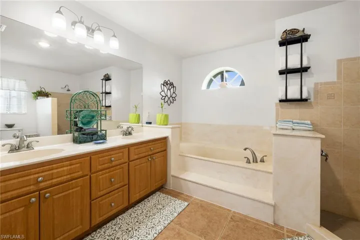 Bathroom with a bath, light tile patterned flooring, double vanity, and walk in shower