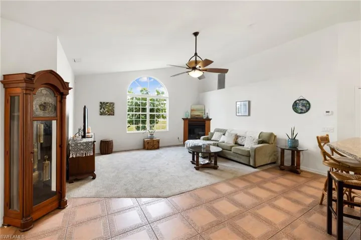 Living room featuring a glass covered fireplace, high vaulted ceiling, and ceiling fan