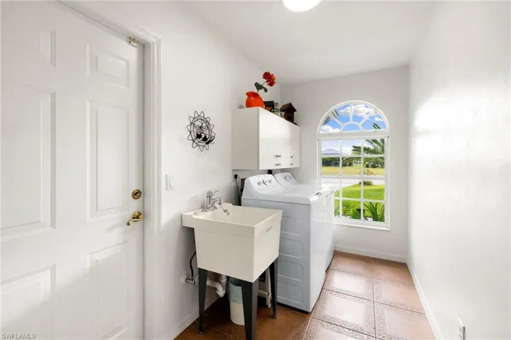 Laundry area featuring cabinet space, light tile patterned flooring, and separate washer and dryer
