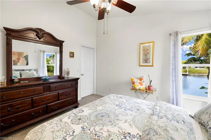 Bedroom with light colored carpet, a ceiling fan, and a high ceiling