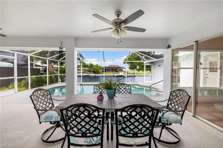 Sunroom with a patio area, a ceiling fan, a water view, and outdoor dining space