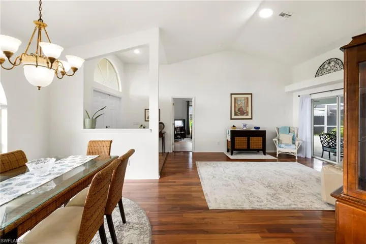 Dining room with dark wood-type flooring, high vaulted ceiling, a chandelier, and recessed lighting