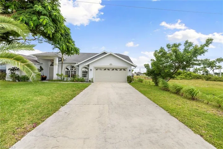 Single story home featuring stucco siding, concrete driveway, a front yard, and an attached garage