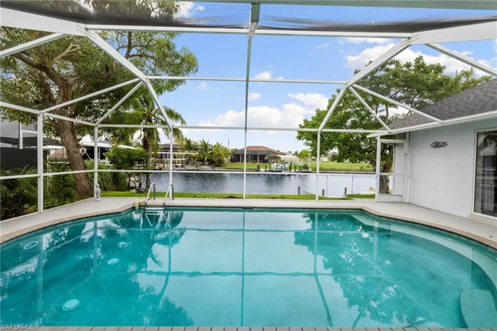 Outdoor pool with a sunroom, a water view, glass enclosure, and a patio