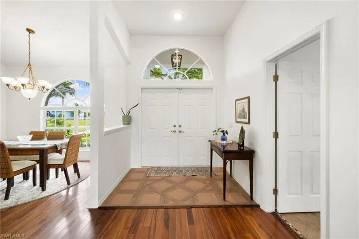 Foyer entrance with plenty of natural light, hardwood / wood-style flooring, a chandelier, a high ceiling, and inlaid floor details