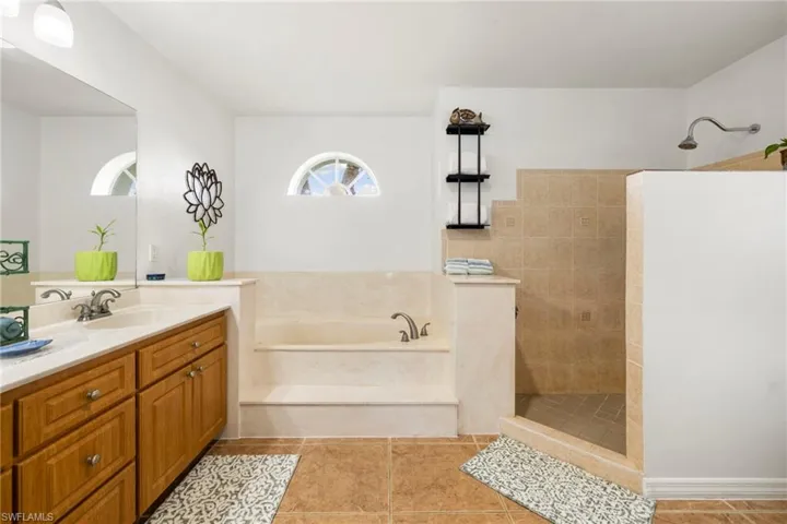 Full bathroom with a walk in shower, a bath, vanity, and light tile patterned floors
