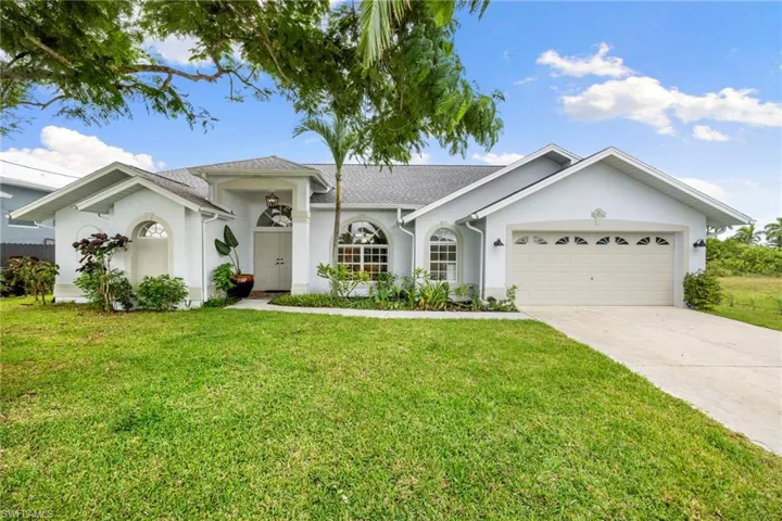 Ranch-style home featuring stucco siding, concrete driveway, a front yard, an attached garage, and a shingled roof
