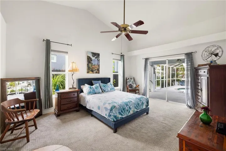 Carpeted bedroom with high vaulted ceiling, a ceiling fan, and access to exterior