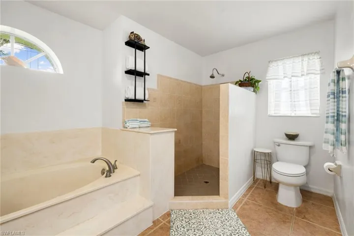 Full bathroom with walk in shower, a bath, and healthy amount of natural light