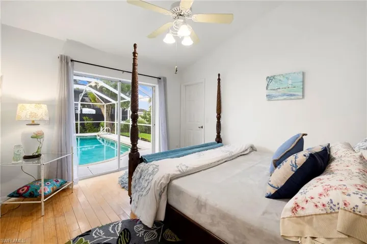 Bedroom featuring lofted ceiling, hardwood / wood-style flooring, access to outside, a ceiling fan, and a sunroom
