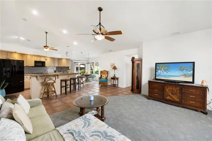 Carpeted living area featuring vaulted ceiling, ceiling fan, recessed lighting, and tile patterned flooring