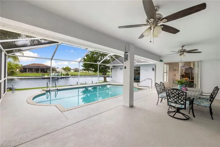 Swimming pool featuring a patio, a water view, a sunroom, and a lanai