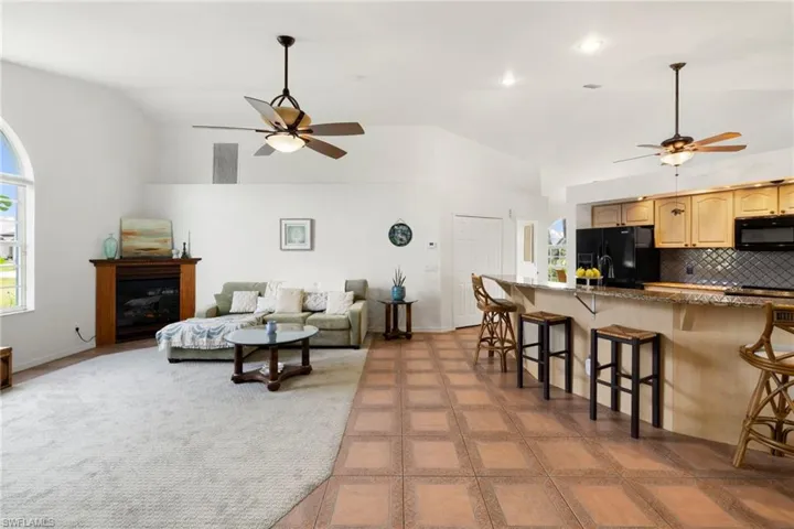 Living area with ceiling fan, high vaulted ceiling, and a glass covered fireplace
